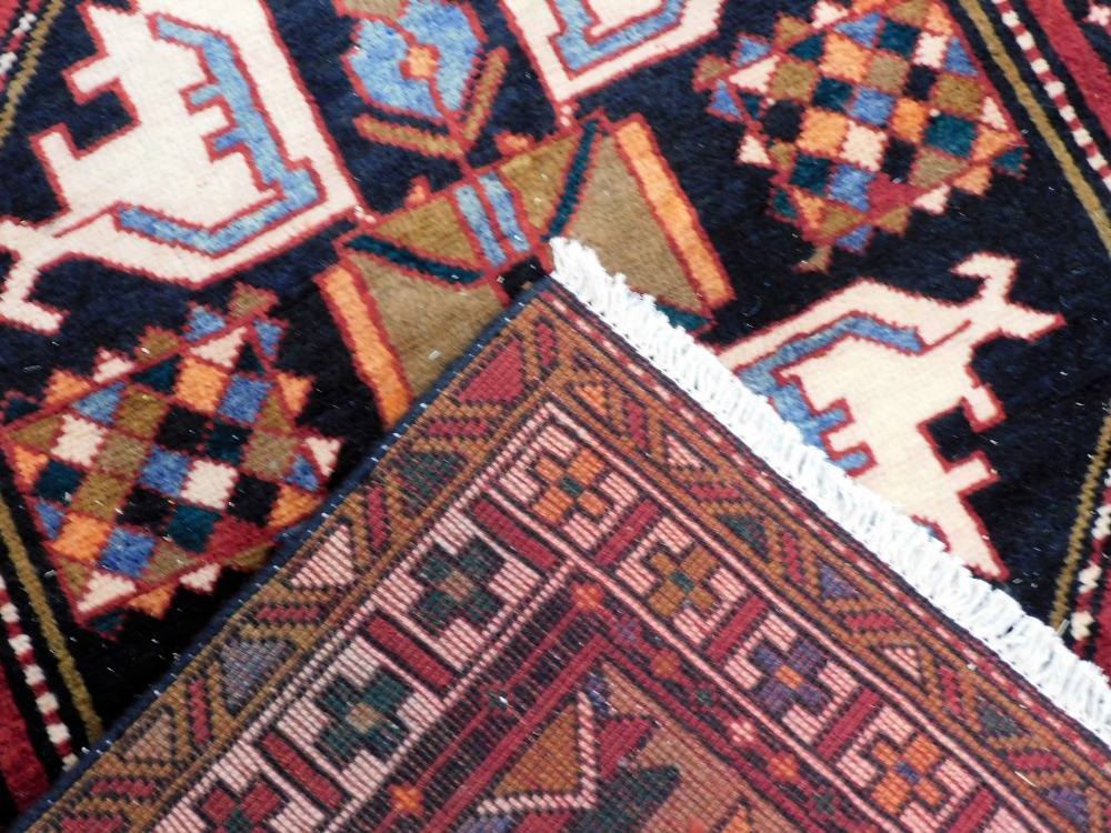 A Northern Persian red ground rug, decorated with geometric floral motifs, within repeating geometri - Image 3 of 3