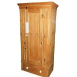 An early 20thC pine single wardrobe, the single door raised above a drawer, with pot castors, 186cm