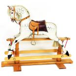 A late 20thC dapple grey rocking horse, on a pine trestle base, approx 134cm long overall, with purc