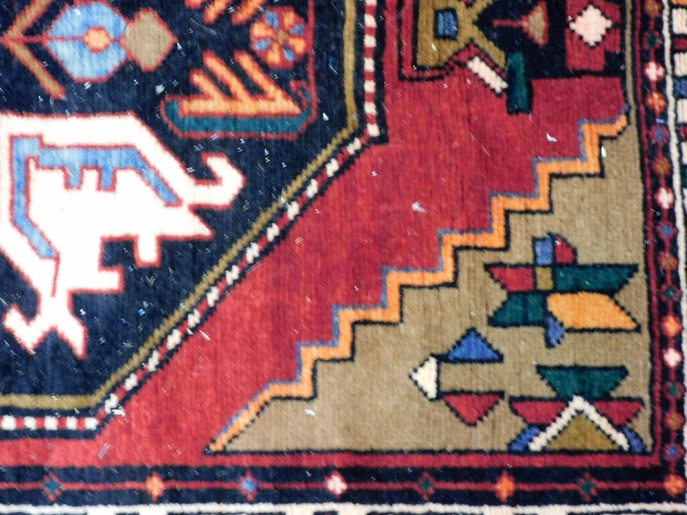 A Northern Persian red ground rug, decorated with geometric floral motifs, within repeating geometri - Image 2 of 3