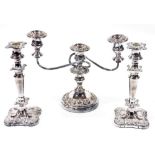 A pair of silver plated candlesticks, each on a shaped square base and a three branch candelabrum. (