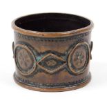 An Arts and Crafts napkin ring, in copper with circular and diamond shaped floral applied decoration