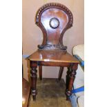 A Victorian mahogany hall chair, with carved shield back and central shield emblem, on tapered legs,