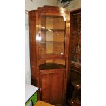 A 1930s oak corner cabinet, the top with a glazed door above a recess and a single hinged door, 194c