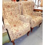 A pair of wing back armchairs, upholstered in floral fabric. The upholstery in this lot does not co