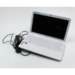 A Toshiba laptop, in white, with charging cable.