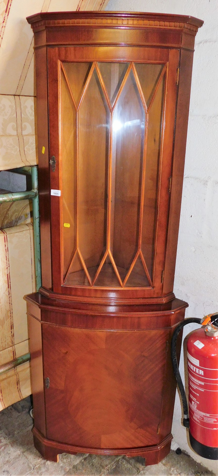 A mahogany corner cabinet, the top with astragal glazed door above a single hinged door, 179cm high.