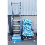 A metal tool box, various garden tools, garden seat with teal leaf pattern upholstery, metal and woo