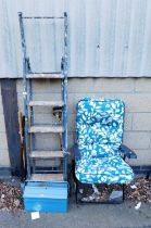 A metal tool box, various garden tools, garden seat with teal leaf pattern upholstery, metal and woo