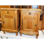 A pair of carved hardwood bedside cabinets, with a frieze drawer above a hinged cabinet, 66cm high,