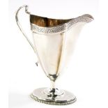 A George V silver cream jug, the helmet shaped body with floral decoration with thumb mould ear hand