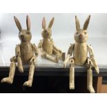 Three wooden carved and painted articulated rabbits one with a minor disability.