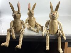 Three wooden carved and painted articulated rabbits one with a minor disability.