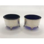Pair of Oval Silver hallmarked salts each on three scroll feet with Blue glass liners