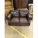 Two seater brown leather sofa on brass castors by Thomas Lloyd