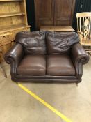 Two seater brown leather sofa on brass castors by Thomas Lloyd