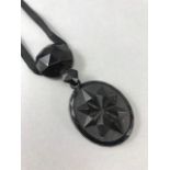 Victorian 3.5" Whitby Jet Pendant hung from a long velvet Ribbon. Main Oval drop approx 5.3cm
