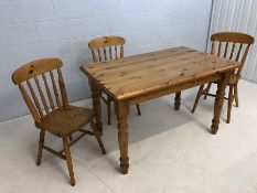 Pine kitchen table and three chairs. Table approx 122cm x 76cm x 76cm tall