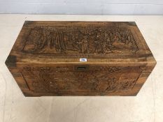 Camphor wood chest heavily carved with oriental scenes with brass fittings (one brass corner