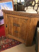 Oak hanging corner cupboard with arts and crafts carved detailing to door, approx 83cm in height