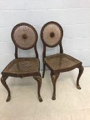 Pair of cane upholstered chairs with cane backs supporting a central wooden mount possibly French