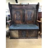 Carved oak settle with high back and padded seat, approx 133cm x 45cm x 150cm tall