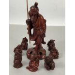 Collection of small cinnabar coloured carvings of buddhas, a seated elephant and a wise man