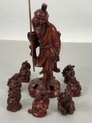 Collection of small cinnabar coloured carvings of buddhas, a seated elephant and a wise man