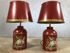 Pair of red Toelware lamps with painted emblem, approx 70cm in height