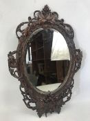 Black Forest bevel edged mirror with carved ornate frame, approx 53cm x 36cm (A/F)