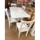 White Ikea folding table with internal drawer space and four white chairs