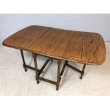 Drop leaf light oak table with turned detailing to legs