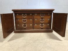 Vintage wooden cabinet with two doors that reveal six drawers with labels