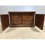 Vintage wooden cabinet with two doors that reveal six drawers with labels