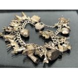 Silver charm bracelet with approx 20 charms mostly marked "silver" (approx 84g)