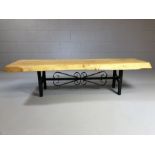 Rustic coffee table on wrought iron base with the top a section of a tree trunk