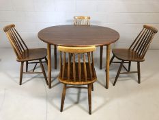 Mid Century circular dining table with drop leaves accompanied by four stick-back dining chairs