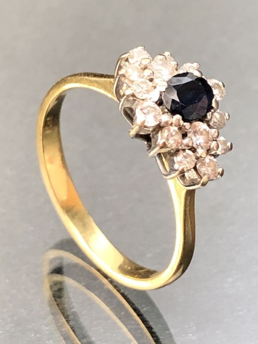 18ct 750 marked Gold ring set with fourteen diamonds surrounding a central Sapphire