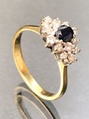 18ct 750 marked Gold ring set with fourteen diamonds surrounding a central Sapphire