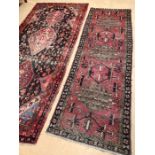 Two large red ground vintage woollen rugs, the first approx 310cm x 138cm, the second 280cm x