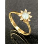18ct Gold Daisy design ring with central light blue stone and surrounded by eight small diamonds (