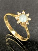 18ct Gold Daisy design ring with central light blue stone and surrounded by eight small diamonds (