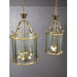 Two brass pendant lights with round glass shades, the larger approx 65cm in drop