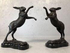 Pair of bronze boxing hares, on marble plinths, each approx 30cm tall