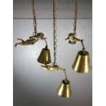 Three decorative brass pendant lights with brass shades held by flying cherubs
