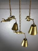 Three decorative brass pendant lights with brass shades held by flying cherubs