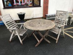 Circular teak folding garden table, approx 120cm in diameter, with two folding chairs