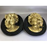 Pair of gilt and black circular plaster decorative wall plaques, each depicting a female head in
