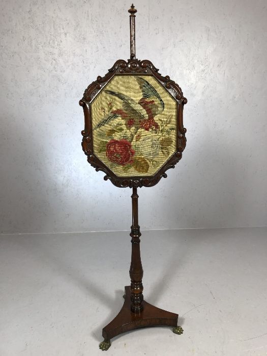 Turned Victorian pole screen on brass lion paw feet with carved frame and tapestry depicting a