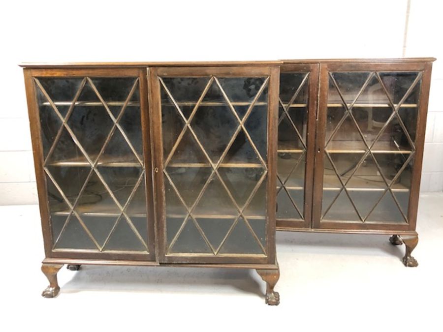 Pair of matching two door glass-fronted display cabinets, each with three shelves, on ball and